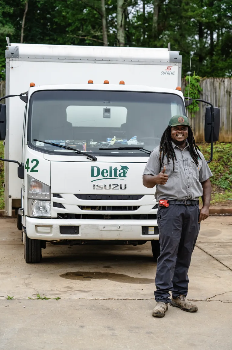 Delta plumber giving a thumbs up in front of a Delta service truck in Stockbridge