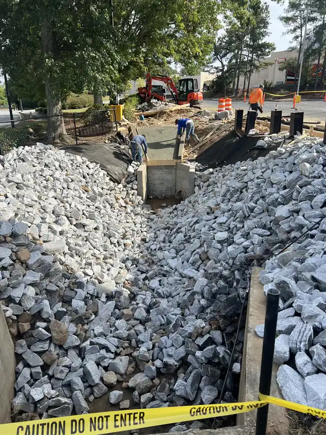 Delta crew working on a retention pond outfall structure lined with stone